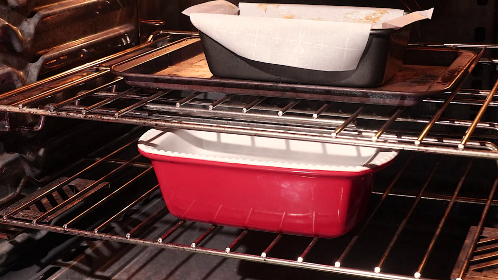 Bake the fruit cake.  Picture showing the fruitcake loaf pan placed on the middle rack and a loaf pan filled with water at the bottom rack of the oven